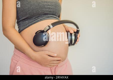 Mélodies dans l'utérus : écouteurs placés sur un ventre enceinte, liaison par la musique, une connexion réconfortante entre mère et bébé Banque D'Images