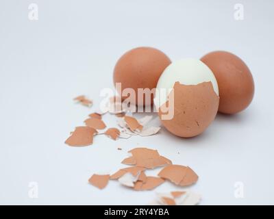 trois œufs de poule bouillis isolés sur blanc, dont un est pelé Banque D'Images
