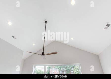 Ventilateur de plafond moderne élégant en bois et noir avec plafond voûté et grande fenêtre moderne Banque D'Images
