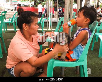 Navotas, Philippines. 28 septembre 2023. Une femme a vu un chien caresser pendant que son fils prend une boisson gazeuse. Dans le cadre de la célébration de la Journée mondiale de la rage, le gouvernement de la ville de Navotas dirigé par le bureau de l'agriculture de la ville de Navotas, a procédé à la vaccination gratuite des chiens et des chats et à l'enregistrement des animaux de compagnie. Ils ont également donné gratuitement de la nourriture pour animaux de compagnie à ceux qui ont participé au programme. Crédit : SOPA Images Limited/Alamy Live News Banque D'Images