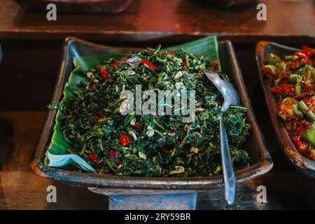 Tumis Kangkung ou Sauteed Kale avec du piment sur la plaque d'argile. Cuisine traditionnelle indonésienne. Banque D'Images