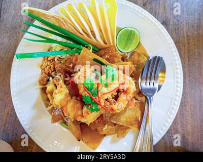 Vue de dessus de délicieux wontons croustillants sautés avec crevettes frites, fleur de banane en fleur, coriandre fraîche, citron et germes de haricots en pla céramique Banque D'Images