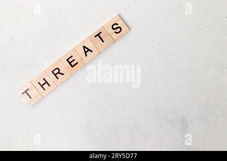 Vue de dessus du mot menaces sur bloc de lettre cube en bois sur fond blanc. Concept commercial Banque D'Images