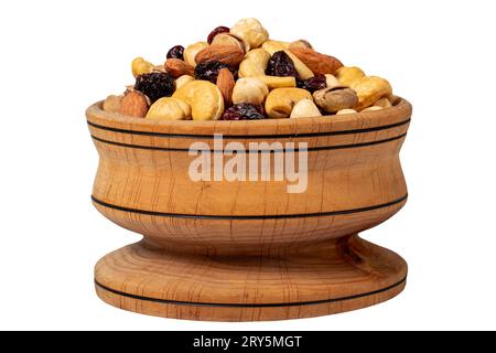 Noix mélangées dans un bol en bois. Noix isolées sur fond blanc. Noix mélangées préparées avec noisettes, amandes, noix de cajou, pistaches, pistaches et raisins Banque D'Images