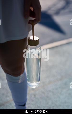 Personne féminine tenant une bouteille d'eau réutilisable en verre dans la main Banque D'Images