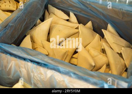 Petits pains triangulaires sucrés semi-finis dans le compartiment réfrigérateur avec un couvercle en verre transparent. Banque D'Images