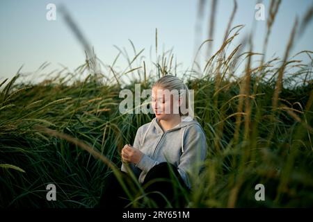 Jeune femme assise dans le champ avec de l'herbe haute Banque D'Images