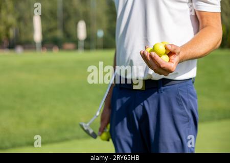 Le golfeur tient beaucoup de balles de golf sur fond d'herbe verte Banque D'Images