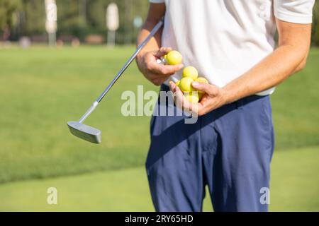 Le golfeur tient beaucoup de balles de golf sur fond d'herbe verte Banque D'Images