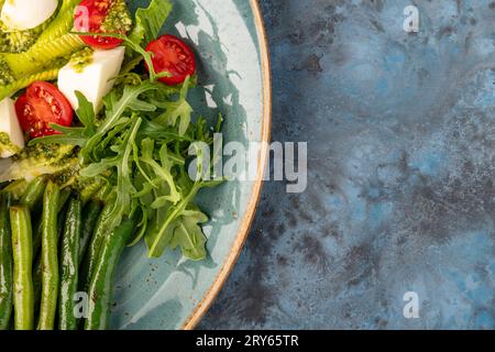 salade d'été diététique avec fromage, asperges, cerise, roquette sur fond gris-bleu. Vue de dessus. espace de copie. service de restaurant Banque D'Images