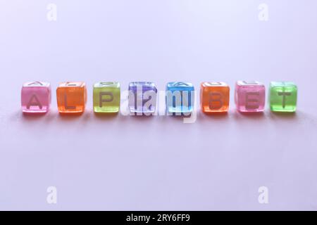 macro plan de perles colorées épelant l'alphabet mot sur un fond rose Banque D'Images