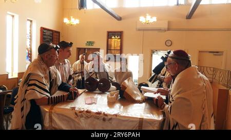 Un grand-père est appelé à lire la Torah par le rabbin lors d'un service en semaine dans la synagogue Solihull et donne ensuite la bénédiction de nommer sa petite-fille avec la mère tenant l'enfant et la grand-mère à côté d'elle. Cette cérémonie simple est suivie de danses joyeuses et de nourriture et de boissons. Banque D'Images