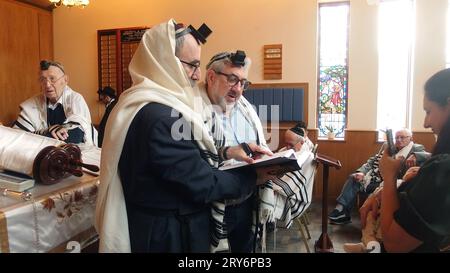 Un grand-père est appelé à lire la Torah par le rabbin lors d'un service en semaine dans la synagogue Solihull et donne ensuite la bénédiction de nommer sa petite-fille avec la mère tenant l'enfant et la grand-mère à côté d'elle. Cette cérémonie simple est suivie de danses joyeuses et de nourriture et de boissons. Banque D'Images