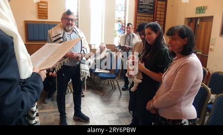 Un grand-père est appelé à lire la Torah par le rabbin lors d'un service en semaine dans la synagogue Solihull et donne ensuite la bénédiction de nommer sa petite-fille avec la mère tenant l'enfant et la grand-mère à côté d'elle. Cette cérémonie simple est suivie de danses joyeuses et de nourriture et de boissons. Banque D'Images