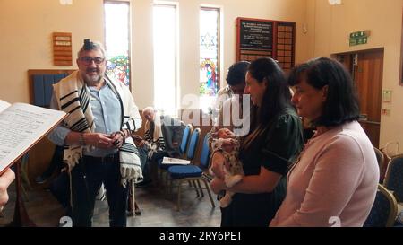 Un grand-père est appelé à lire la Torah par le rabbin lors d'un service en semaine dans la synagogue Solihull et donne ensuite la bénédiction de nommer sa petite-fille avec la mère tenant l'enfant et la grand-mère à côté d'elle. Cette cérémonie simple est suivie de danses joyeuses et de nourriture et de boissons. Banque D'Images