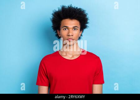 Portrait de drôle multinational jeune gars sérieusement regarder caméra porter rouge décontracté t-shirt isolé fond de couleur pastel bleu Banque D'Images