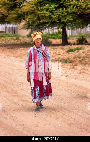 basarwa vieille femme africaine marchant sur un chemin de terre dans le village traditionnel Banque D'Images