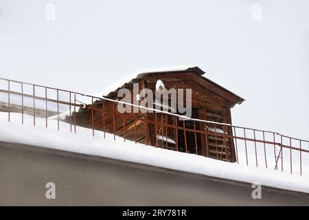 Pigeonnier en bois ou maison d'oiseau sur le toit de la maison avec clôture. Neige, hiver. Espace de copie Banque D'Images