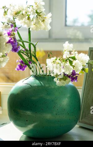 Fleurs sèches dans un vase rond en céramique turquoise. Banque D'Images