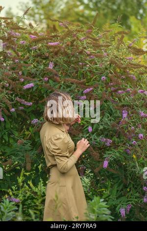 Femme dans les fleurs ensoleillées champ de la Buddleia. Bonne jeune fille dans le domaine. Banque D'Images