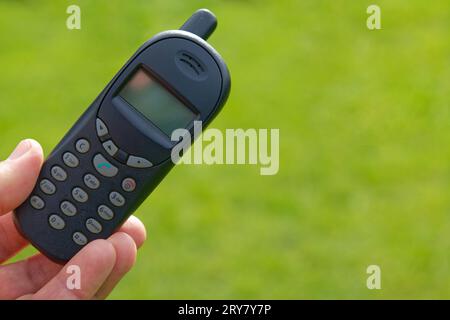 Un vieux téléphone portable à bouton-poussoir dans une main Banque D'Images