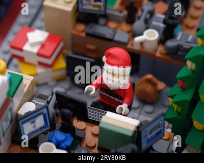 Tambov, Fédération de Russie - 26 septembre 2023 Une minifigurine Lego du Père Noël travaillant sur un ordinateur dans son bureau entouré de cadeaux de Noël. Banque D'Images