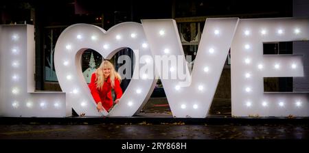 Femme à l'intérieur de la forme de coeur de lettres d'amour illuminées Banque D'Images