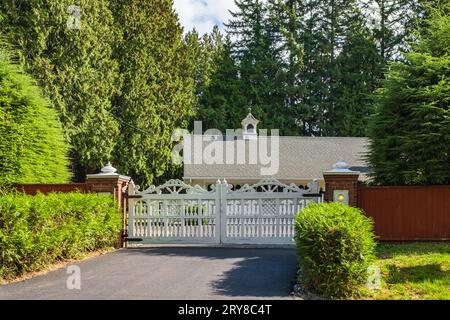 Entrée fermée avec allée routière dans la campagne rurale du Canada avec clôture en bois et arbres luxuriants verts en été. Portes pour une maison de campagne en milieu rural Banque D'Images