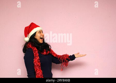 Jeune femme adolescente avec chapeau de santa montre son enthousiasme pour l'arrivée de décembre et célébrer noël Banque D'Images