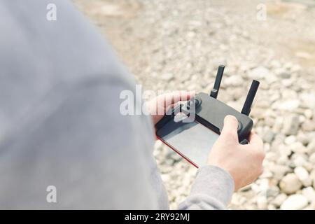 Mains masculines tenant la télécommande Dron faisant quelques réglages prêts à l'exécuter dans le ciel. Photo recadrée d'un homme réglant la radio de télémétrie numérique Banque D'Images
