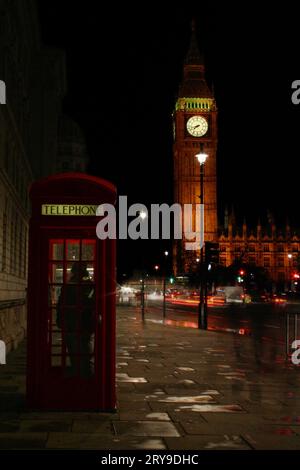 Cabine téléphonique rouge traditionnelle avec Big Ben derrière la nuit. Banque D'Images