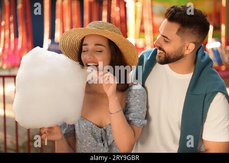 Heureux jeune homme et sa petite amie mangeant des bonbons de coton à funfair Banque D'Images