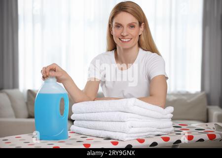 Femme avec assouplissant et serviettes propres dans la chambre, espace pour le texte Banque D'Images