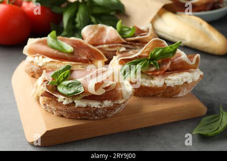 Sandwichs savoureux avec jambon séché et basilic sur la table grise, gros plan Banque D'Images