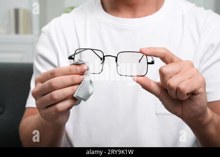 Homme essuyant les lunettes avec un chiffon en microfibre à l'intérieur, gros plan Banque D'Images