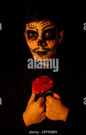 Portrait de Mexicain habillé en catrin avec fleur rouge sur fond noir dans une tenue élégante Banque D'Images