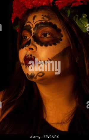 fille avec le maquillage catrina représenté sur un fond sombre et regardant sur le côté Banque D'Images