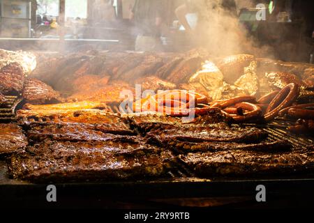 Une délicieuse gamme de viandes cuisant sur un four à feu chaud disponible dans un restaurant animé Banque D'Images