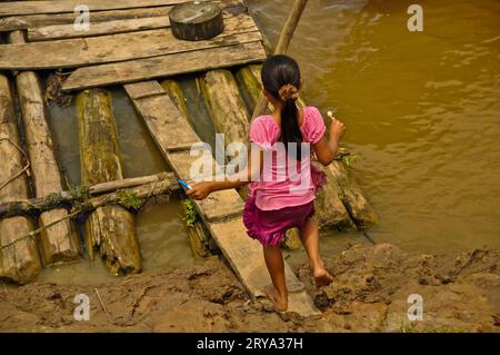 Jeune fille marchant vers Riverbank, Amazon Village, Pérou Banque D'Images