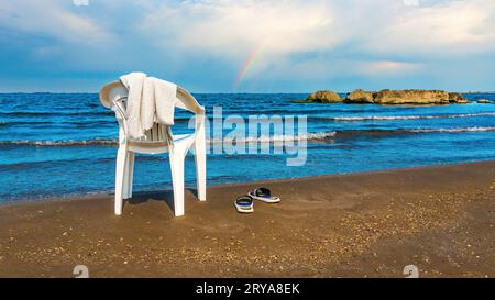 Coucher de soleil paysage côtier avec une chaise solitaire sur une plage de sable de la mer Méditerranée Banque D'Images