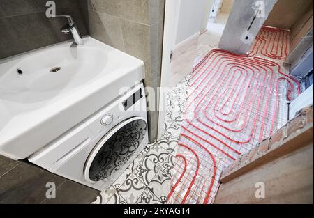 Comparaison des toilettes avant et après rénovation. Ancien appartement toilettes avec tuyaux de chauffage au sol et nouvelle chambre rénovée avec lavabo et machine à laver. Banque D'Images