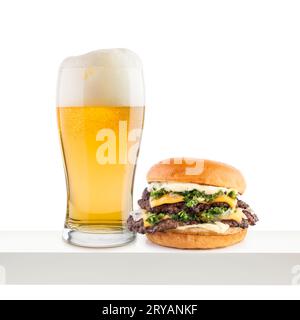 Pinte de bière lager avec hamburger classique sur étagère blanche. Banque D'Images