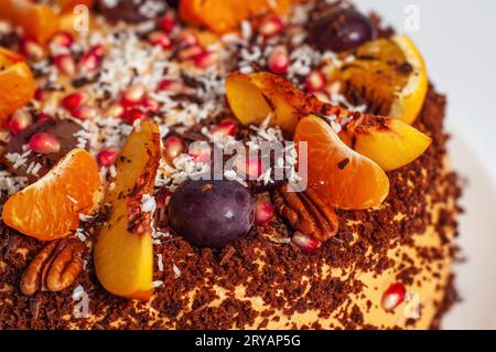 Gâteau fait à la main avec des saupoudrages de chocolat et décoration de fruits frais, fragment et gros plan, sur fond blanc Banque D'Images