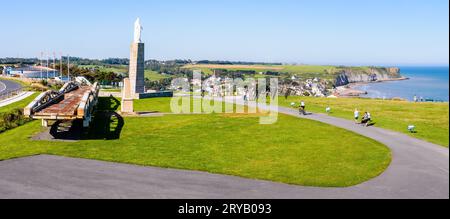 Vue sur Arromanches et le Cap Manvieux en Normandie avec deux travées de pont de baleine, le Mémorial des ingénieurs royaux et la statue de la Vierge Marie. Banque D'Images