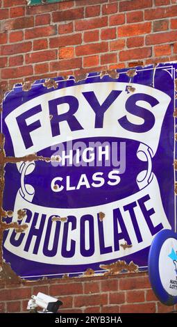 Un panneau publicitaire coloré, vintage, en métal affiché sur un mur de briques chocolat Fry, décrit sur la publicité comme de grande classe Banque D'Images