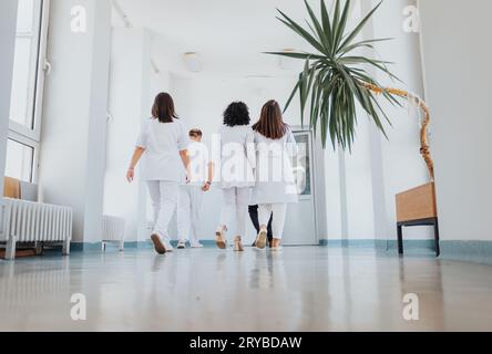 Médecins expérimentés en uniformes médicaux marchant avec confiance dans le couloir de l'hôpital. Portrait souriant d'un médecin d'âge moyen satisfait. Banque D'Images