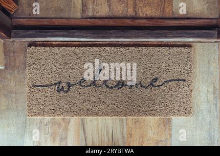 Tapis de bienvenue devant la porte au-dessus du plancher en bois Banque D'Images