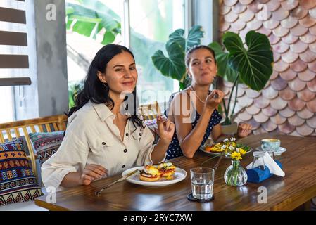 deux belles femmes amies mangeant le petit déjeuner dans le café et parlant Banque D'Images