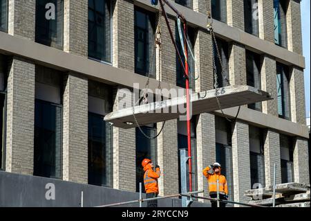 Deux ouvriers de la construction supervisent une dalle de béton qui est abaissée en position, Glasgow, Écosse, Royaume-Uni, Europe Banque D'Images