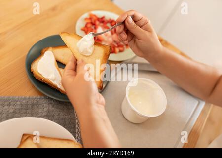 vue de dessus, une femme étale de la crème sure sur des toasts et met des fraises dessus Banque D'Images